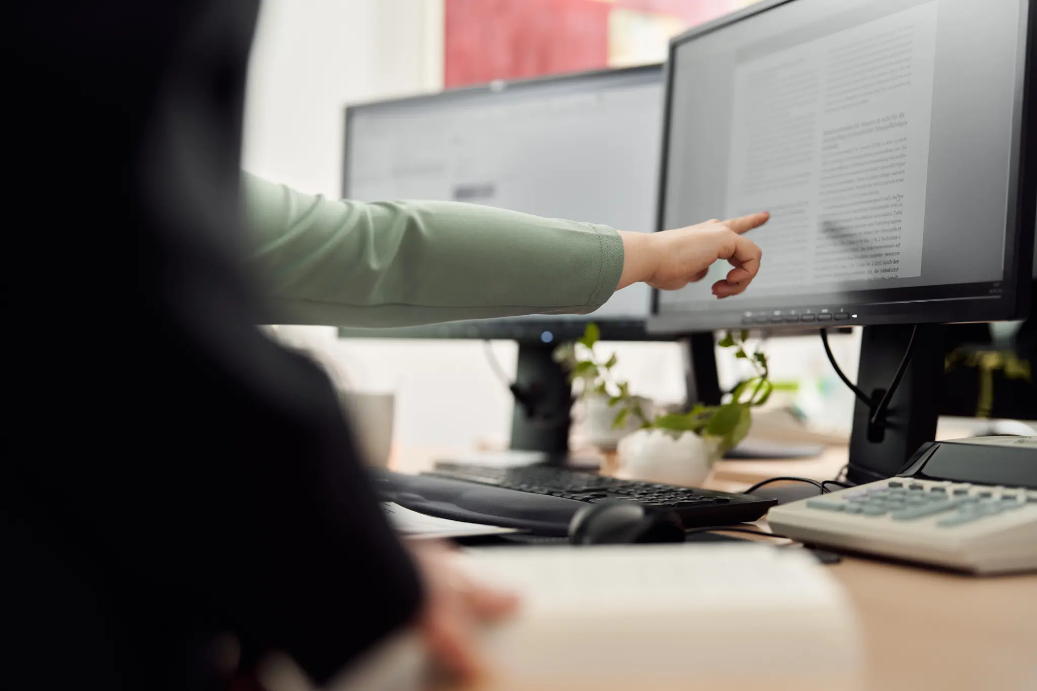 Partner Kanzlei Goertz Klingen Tilg zeigt vor seinen Mitarbeitern auf einen Bildschirm